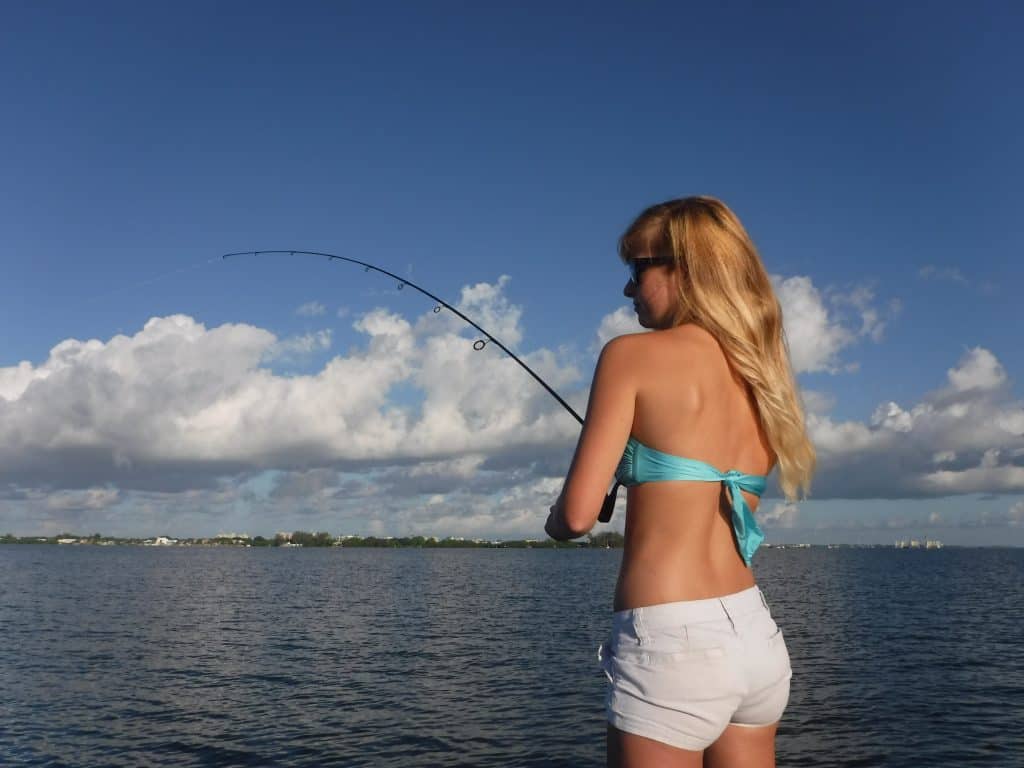 Beach lady casting fishing rod Stock Photo